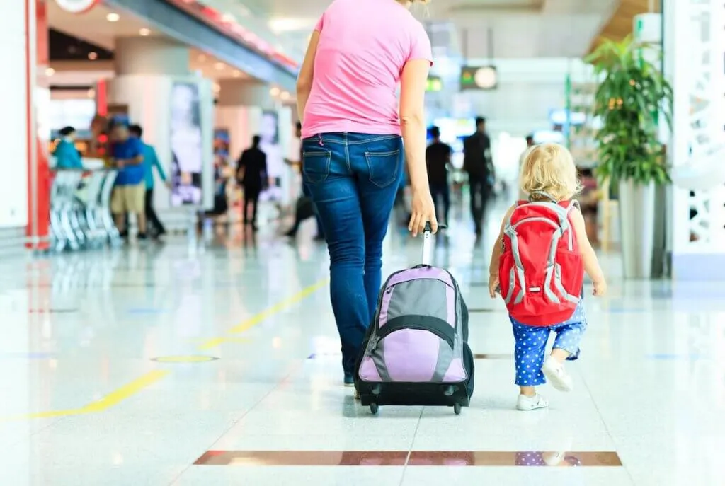 Image of mother and little daughter walking in the airport, family travel