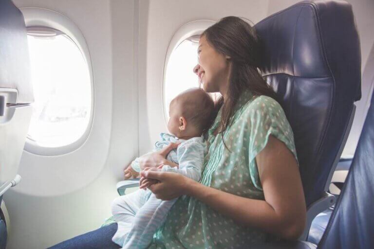 Find out my top tips for flying with a baby on an airplane. Image of a woman holding an infant on an airplane