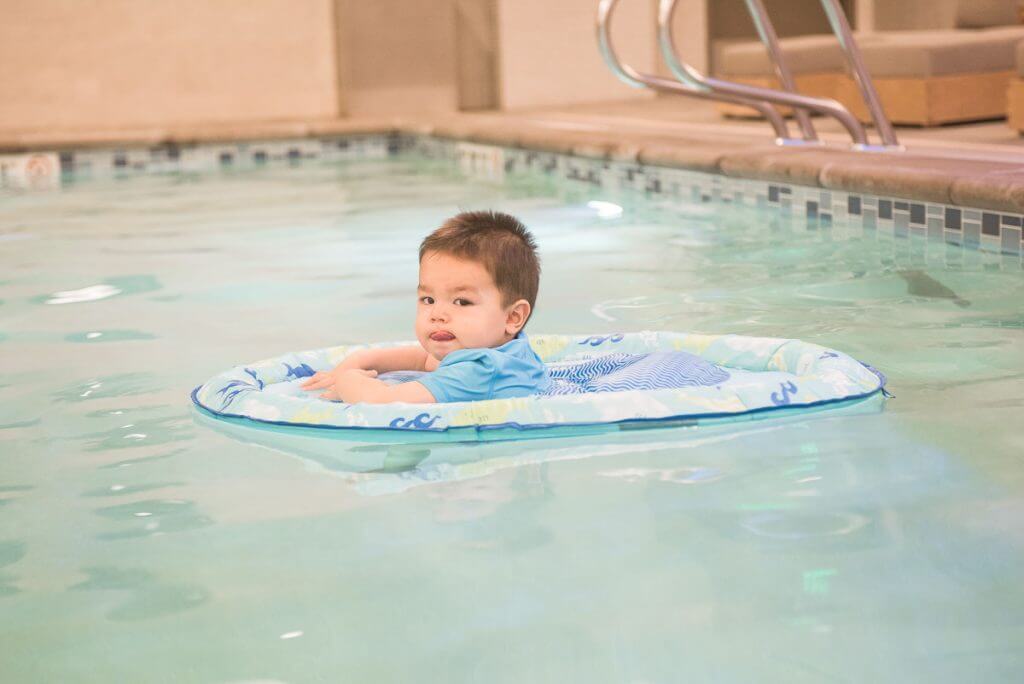 Photo of a baby using a baby float ring in a swimming pool SwimWays #BabySpringFloat #SpringFloat #NationalLearnToSwimDay #FloatwithSwimWays #IC