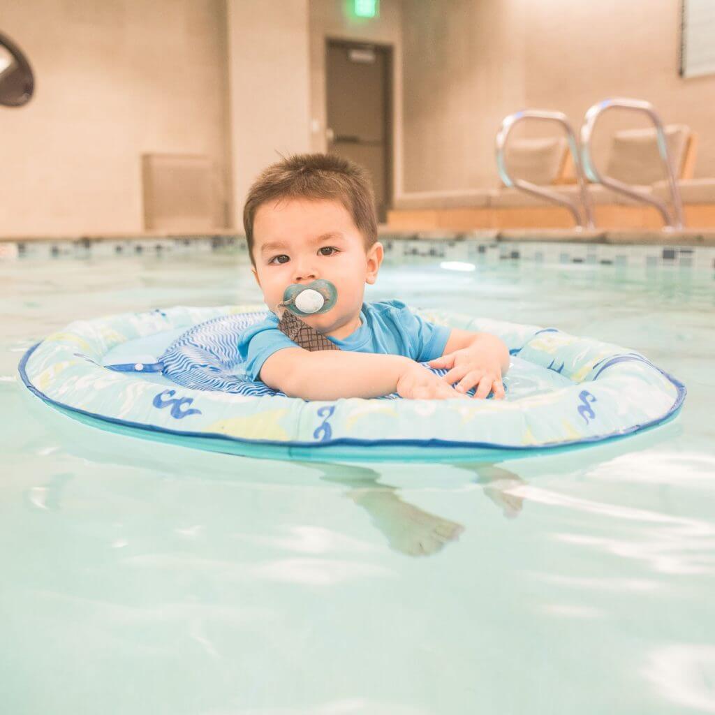 Photo of a baby swimming in a hotel pool in a Swimways pool float #swimways #babyswimming #binky #staycation #summertravel