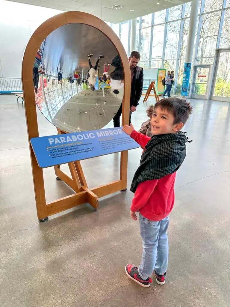 Image of a boy in front of a parabolic mirror at the Pacific Science Center