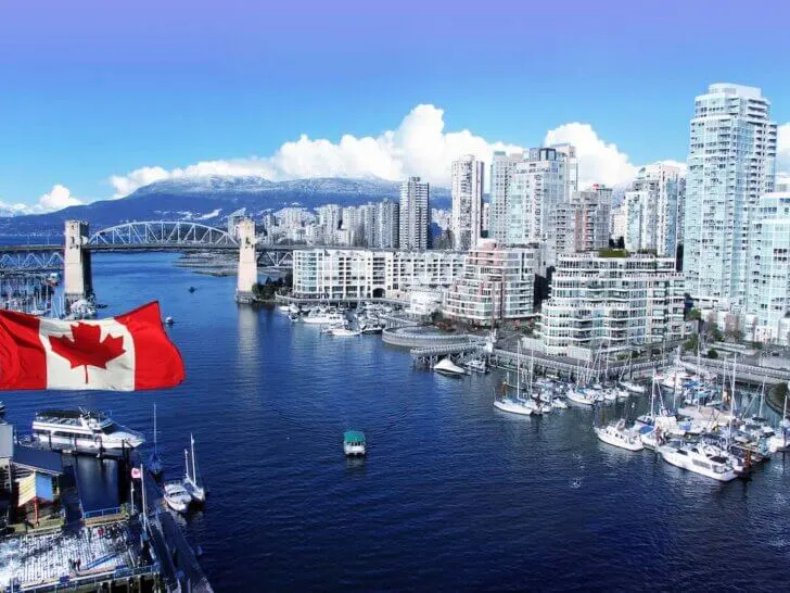 Check out this amazing 4-day Vancouver itinerary with kids by top Seattle blog Marcie in Mommyland. Image of Canadian flag in front of view of False Creek and the Burrard street bridge in Vancouver, Canada.