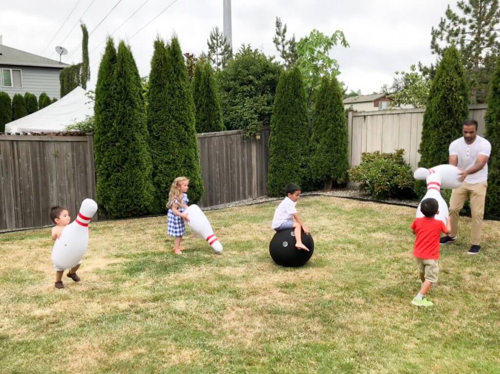 Photo of kids playing with inflatable bowling set from Zulily at a 4th of July BBQ #zulily #bowlingpins #lawngames #inflatable