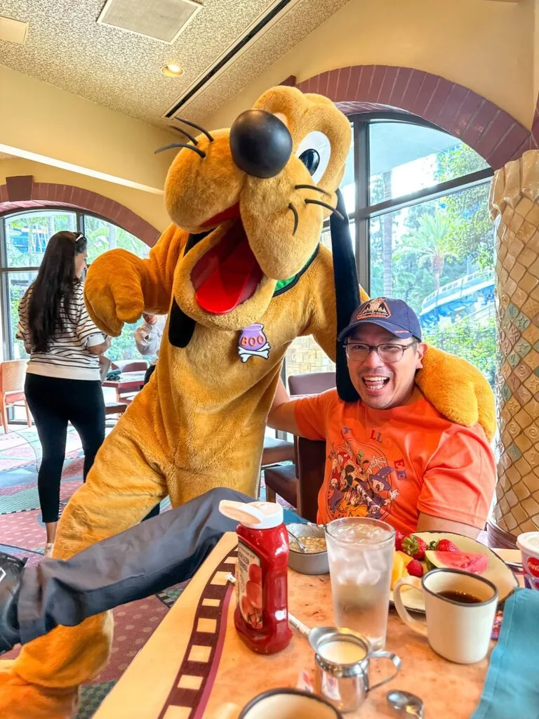 Image of a man and Pluto at Goofy's Kitchen character meal at Disneyland