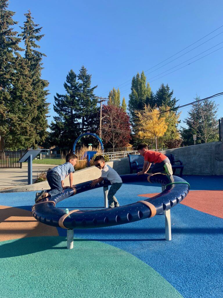 Photo of kids playing with a spinning ring at Meadow Crest inclusive playground near Seattle, WA #inclusiveplayground #playground #preschoolers