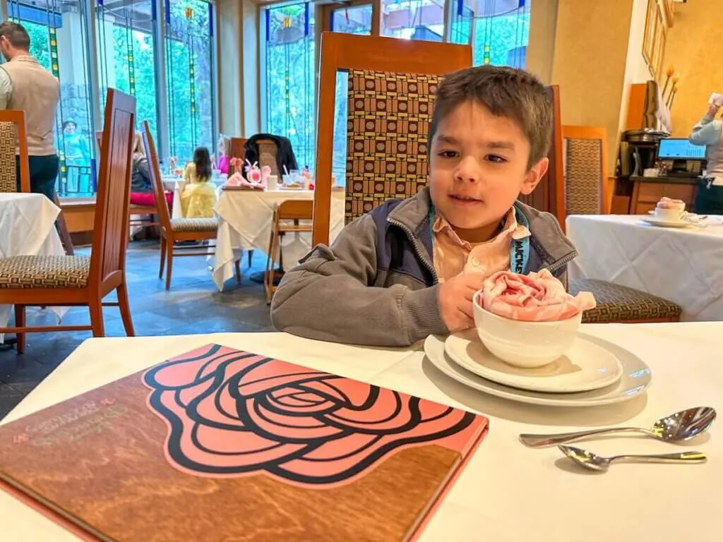 Image of a boy at a table with a napkin in the shape of a rose in a tea cup