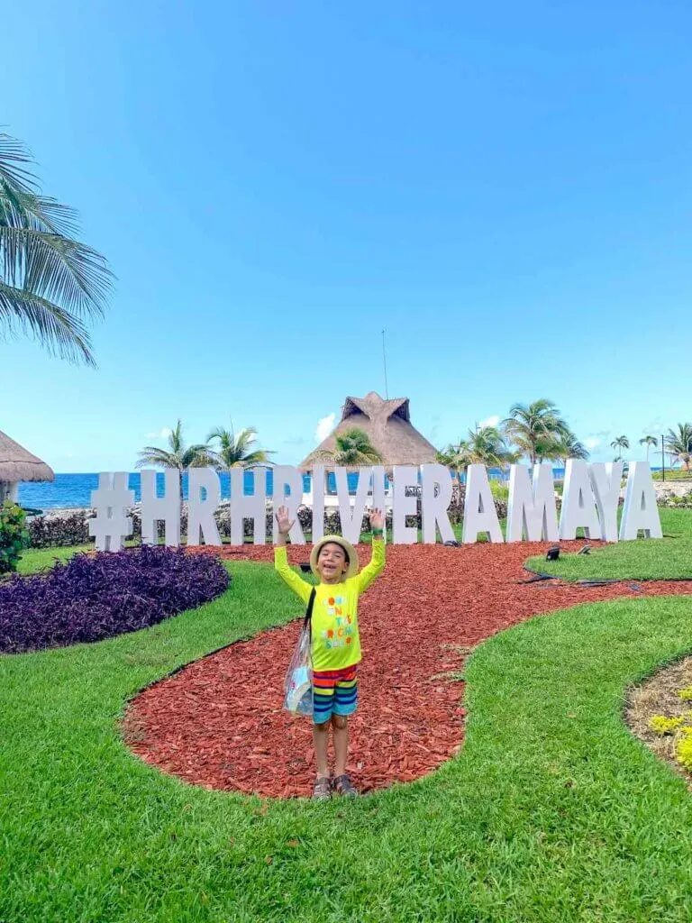 Image of a boy standing in front of a Hard Rock Riviera Maya sign
