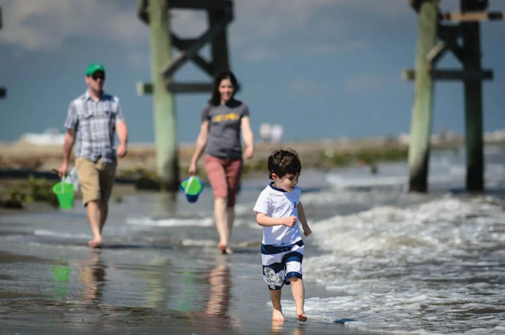 The Best Warm Places to Visit in December in the USA featured by top US travel blogger, Marcie in Mommyland: Family on the beach in Grand Isle, Louisiana. 
