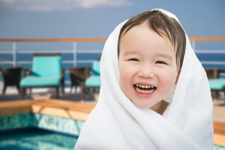 Best Cruises for Toddlers this Year featured by top US family travel blogger, Marcie in Mommyland: Happy Cute Mixed Race Chinese and Caucasian Boy On Cruise Ship Wrapped In A Towel.