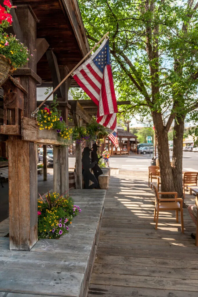 wooden sidewalk with American flags and  sculptured silhouettes in Winthrop, Washington State, USA