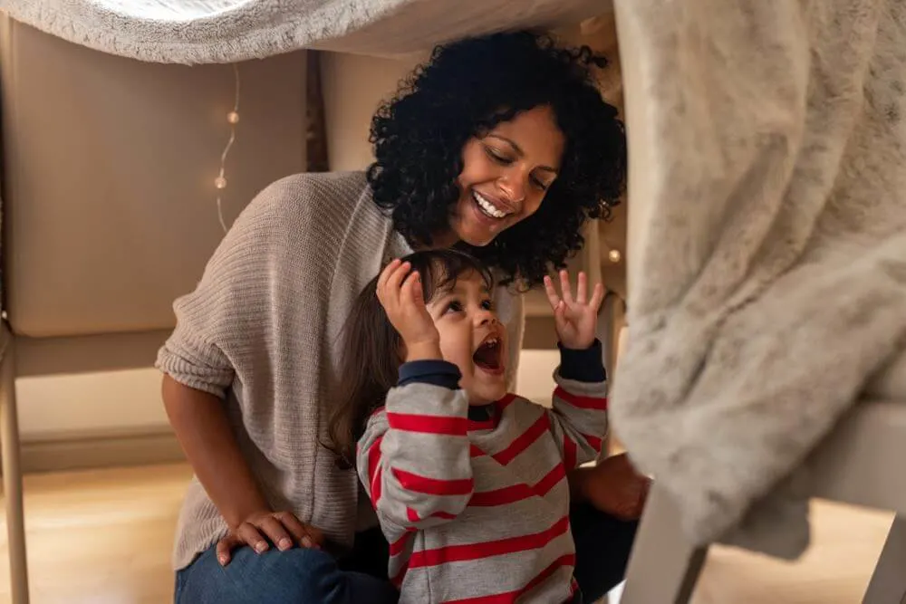 Fun Things to Do at Home on Halloween with Kids featured by top Seattle lifestyle blogger, Marcie in Mommyland. One of the easiest Halloween activities for kids is making a blanket fort. Image of a mother and child playing in a blanket fort 