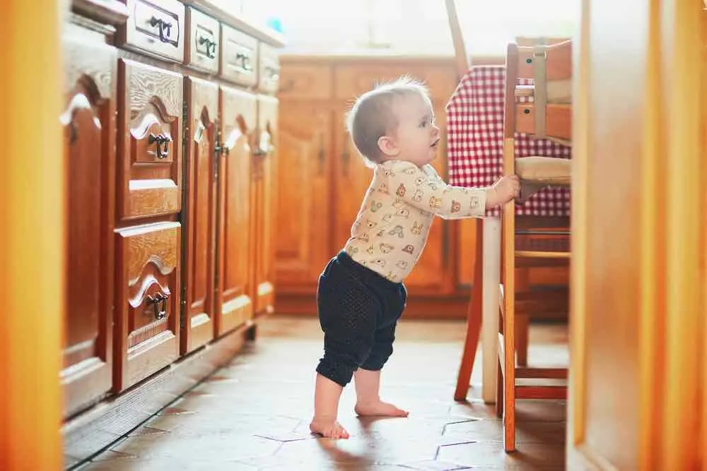 10 Best Secret Places to Hide Christmas Presents featured by top US lifestyle blogger, Marcie in Mommyland featured by top Seattle lifestyle blogger, Marcie in Mommyland: Find out how to babyproof your home for Christmas. Image of Baby girl standing on the floor in the kitchen and holding on to furniture. Little child oulling up at home