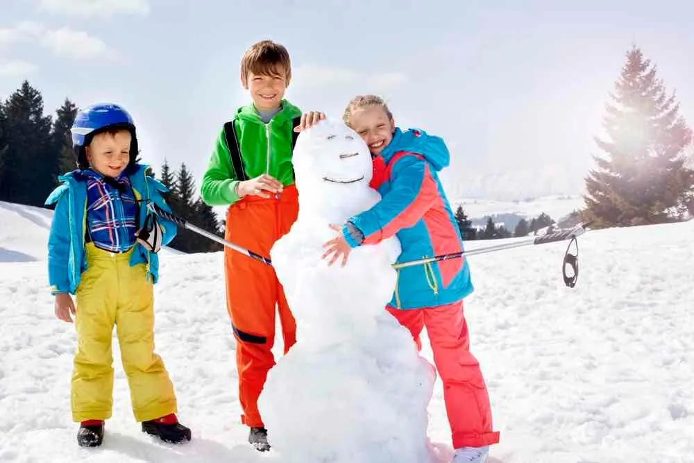 Building a snowman is the ultimate Christmas tradition with kids. Image of brothers and sister building a snowman