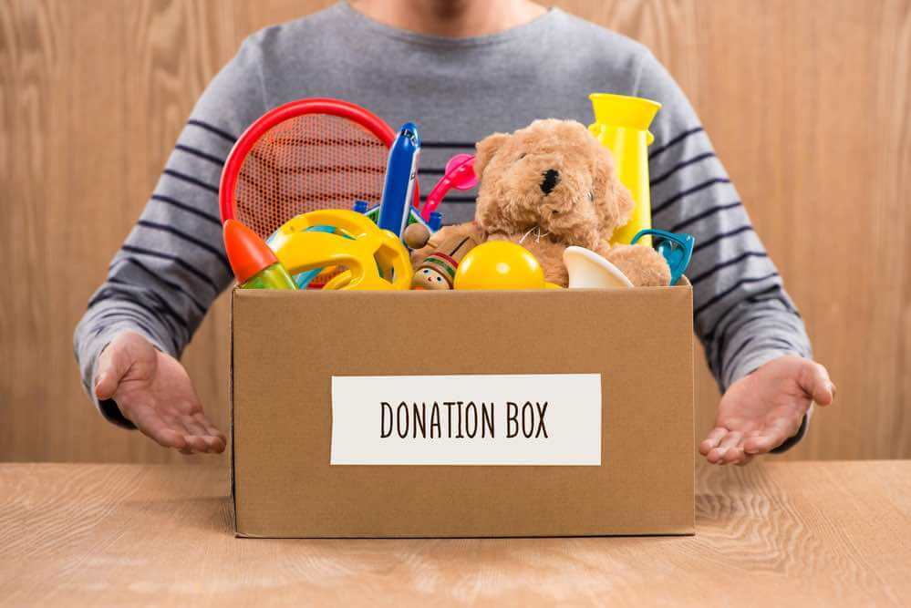 15 Free Festive Christmas Traditions That Don't Cost a Dime featured by top Seattle lifestyle blogger, Marcie in Mommyland: Donating toys is an easy way kids can volunteer this holiday season. Image of Male volunteer holding donation box with old toys.