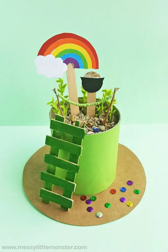 Find out how to make a leprechaun trap with this easy leprechaun trap tutorial. Image of a colorful rainbow and pot of gold on popsicle sticks in a planter.