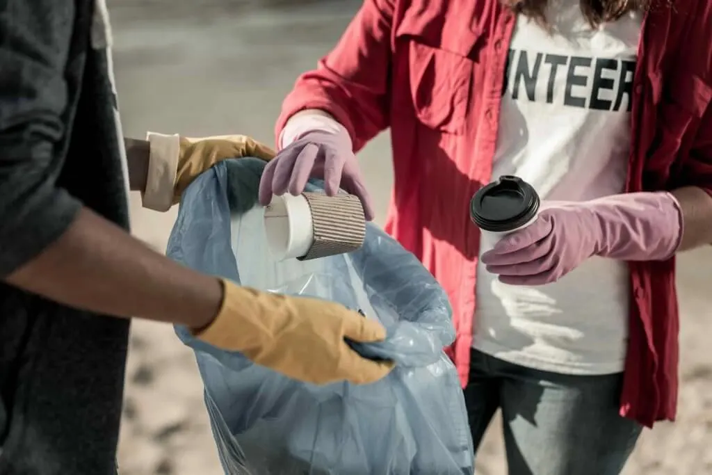 Another way to celebrate Earth Day with kids is to do a beach clean up. Image of a boy and girl wearing gloves participating in voluntary cleaning action on the beach together