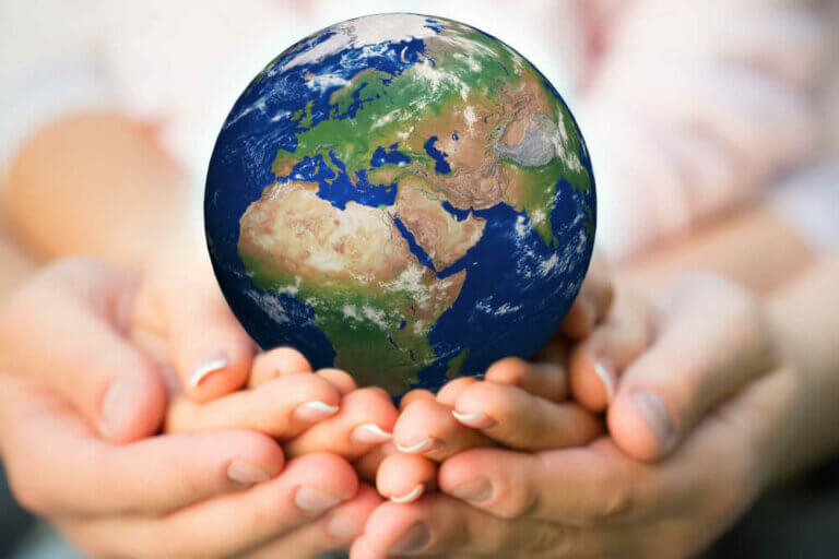 Find out 10 easy Earth Day activities for kids by top Seattle blog Marcie in Mommyland. Image of a family holding Earth in their hands.
