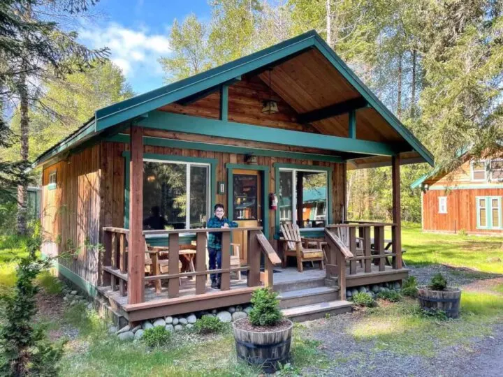 Find out why we think Stone Creek Lodge is one of the best Mt Rainier cabins for families. Image of a kid posing on the porch of a Mount Rainier cabin.