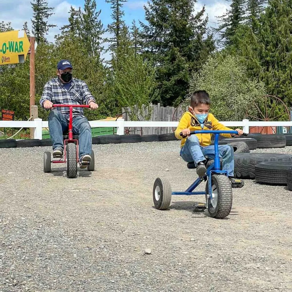 Maris Farms is one of the best places to go in South Sound. Image of a dad and son each riding tricycles at Maris Farms in Buckley, WA.