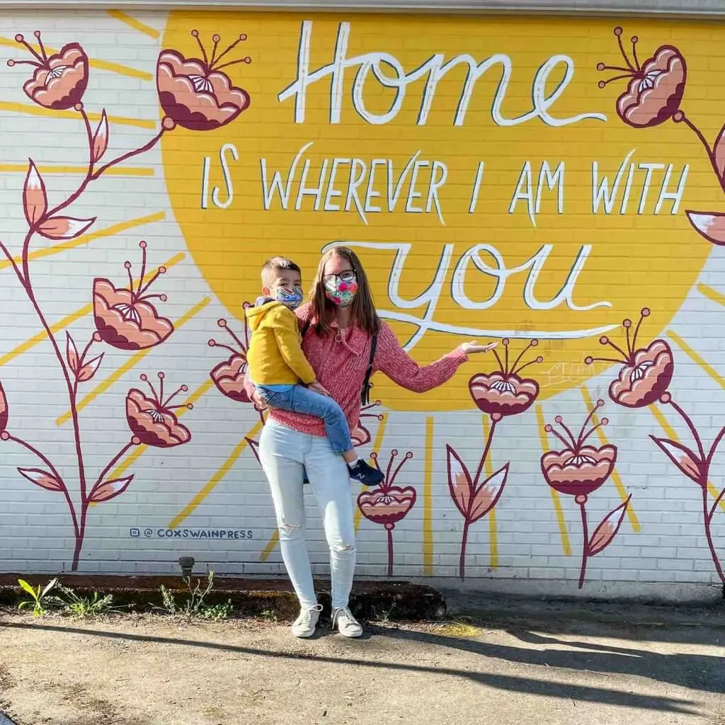 There are lots of amazing murals in Sumner like this one. Image of a mom and boy posing in front of a mural that says "home is wherever I am with you"