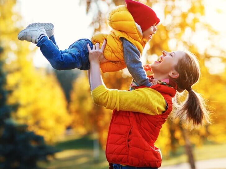 Get my free fall bucket list and free fall scavenger hunt printables by top Seattle blog Marcie in Mommyland. Image of happy family mother and baby son playing and laughing on autumn walk