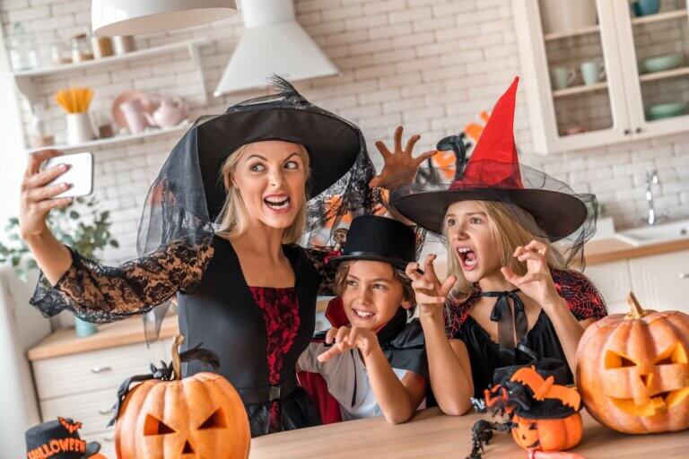 Fun Things to Do at Home on Halloween with Kids featured by top Seattle lifestyle blogger, Marcie in Mommyland. Image of a mom and two kids taking a selfie dressed up in Halloween costumes
