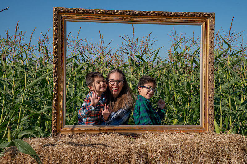 Image of a large empty picture frame with a mom and two boys poking their heads through.