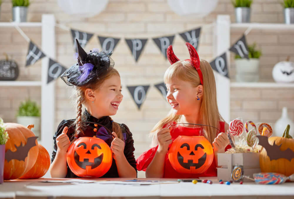 Get some easy Disney Halloween party ideas from top Seattle blog Marcie in Mommyland. Image of two girls dressed in Halloween costumes with jack-o-lanterns in front of them