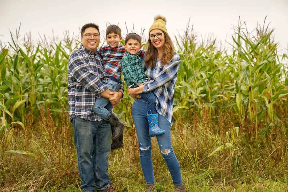 Image of a family wearing plaid standing in front of a cornfield.