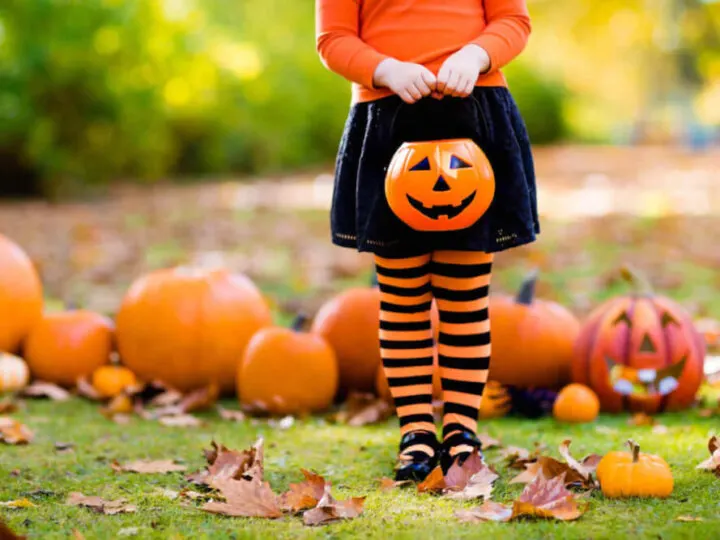 Find out the best non-candy Halloween treats for trick-or-treaters recommended by top Seattle blog Marcie in Mommyland. Image of a girl holding a plastic pumpkin treat container.