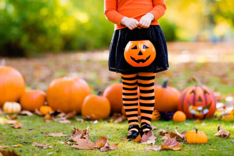 Find out the best non-candy Halloween treats for trick-or-treaters recommended by top Seattle blog Marcie in Mommyland. Image of a girl holding a plastic pumpkin treat container.