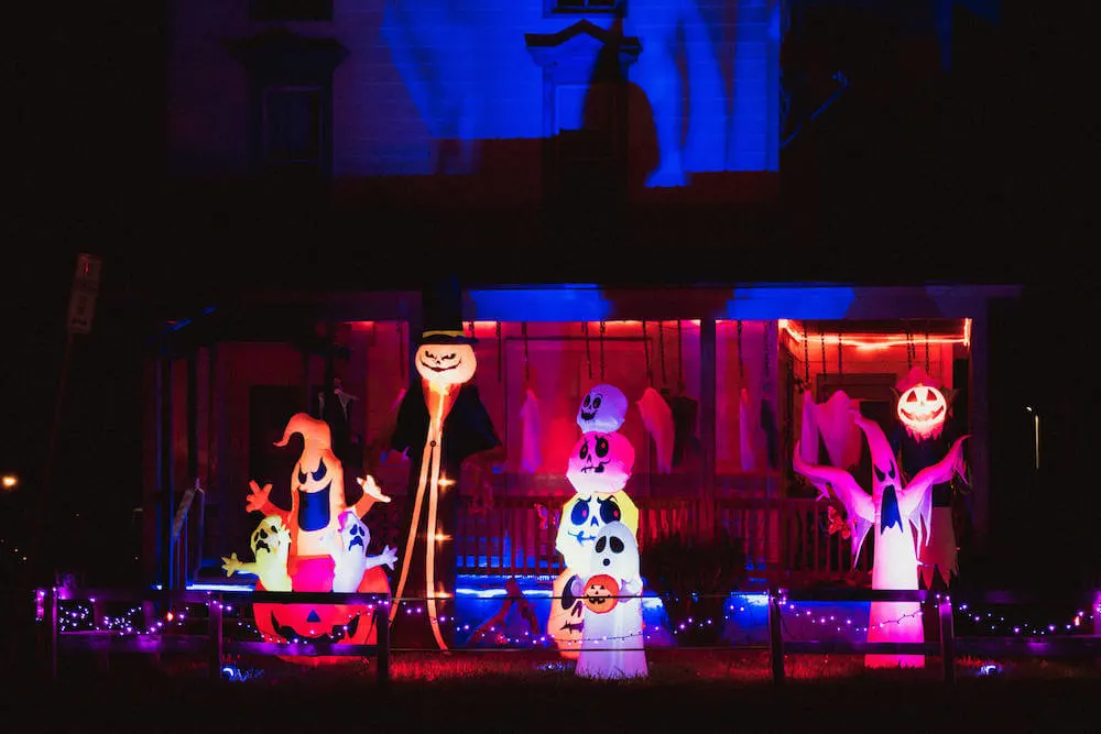 One of the best Halloween lighting ideas is to use inflatables! Image of a porch filled with Halloween inflatables like ghosts, pumpkins, and more.