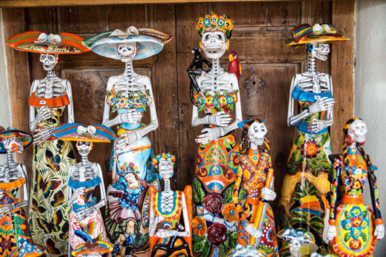 Find out the best small towns in Mexico for celebrating Day of the Dead. Image of brightly colored skeleton decorations in Mexico for Dia de los Muertos.