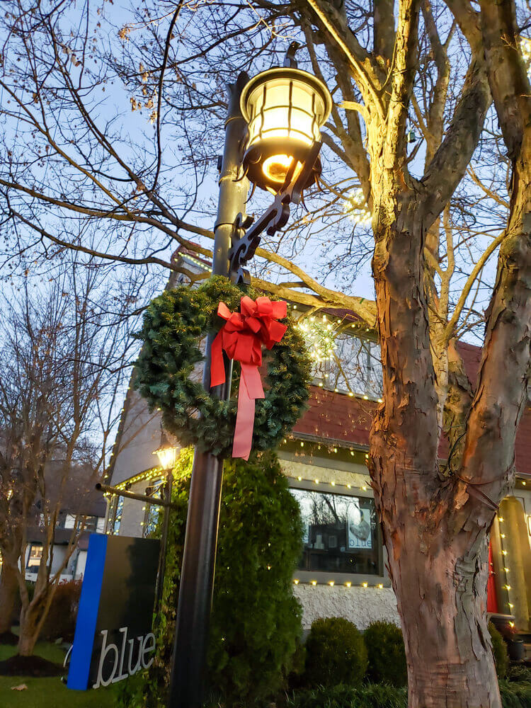 Asheville North Carolina is one of the best Christmas destinations in the United States. Image of a Christmas wreath with a red bow on a lamp post.