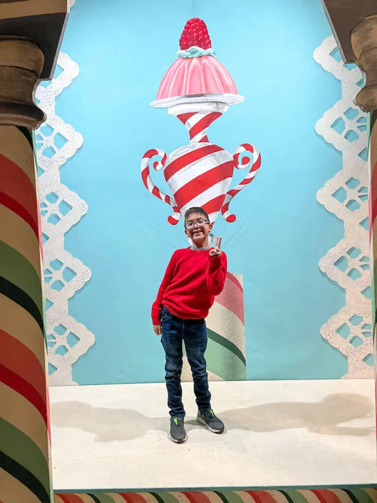 Image of a boy wearing a red sweater standing in a smaller version of the Ian Falconer designed set.