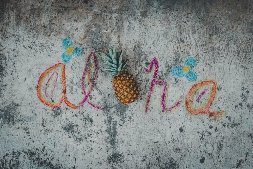 Image of the word Aloha spelled out with colorful chalk and a pineapple for the O