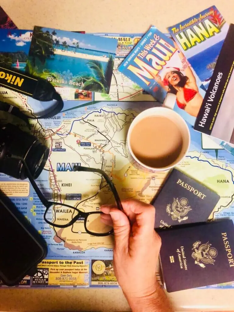 Image of a bunch of Hawaii maps, brochures, passports, camera, coffee and glasses as a flat lay image.