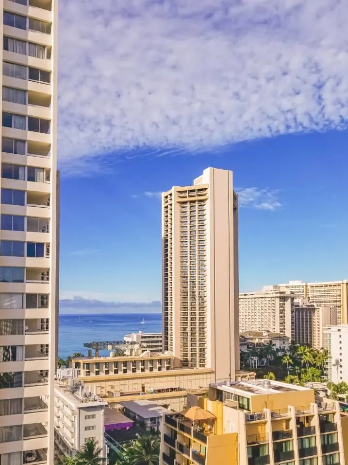 Image of a bunch of Waikiki hotels and buildings with the ocean and blue sky in the background.