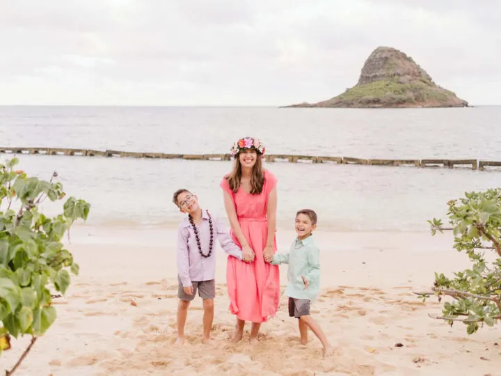 Find out the best Hawaiian island for kids recommended by a mom who's visited Hawaii more than 35 times! Image of a mom and two boys holding hands at Kualoa Beach Park on Oahu.