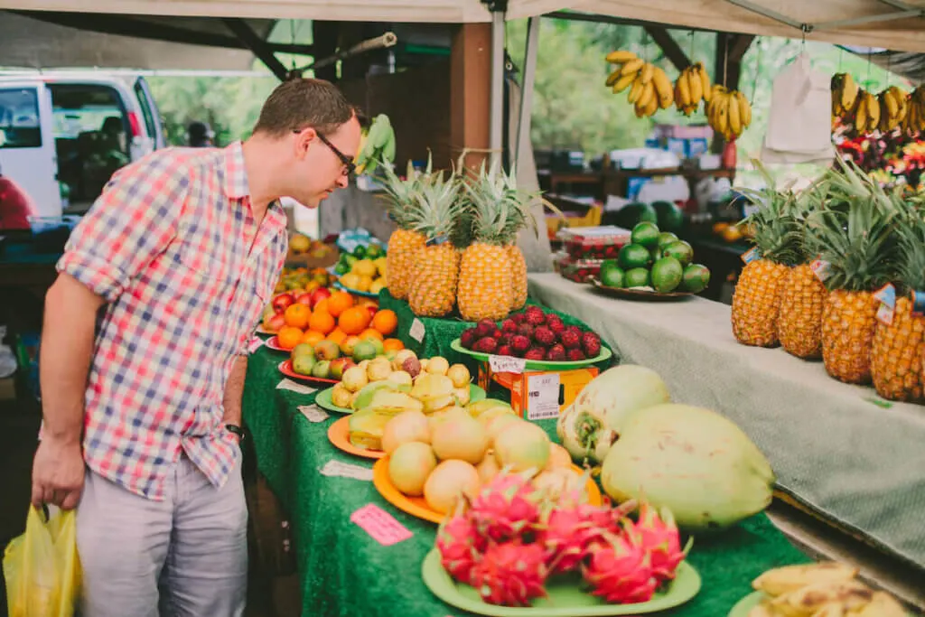 Image of a man shopping for fruit at a Big Island farmers market in Hawaii.