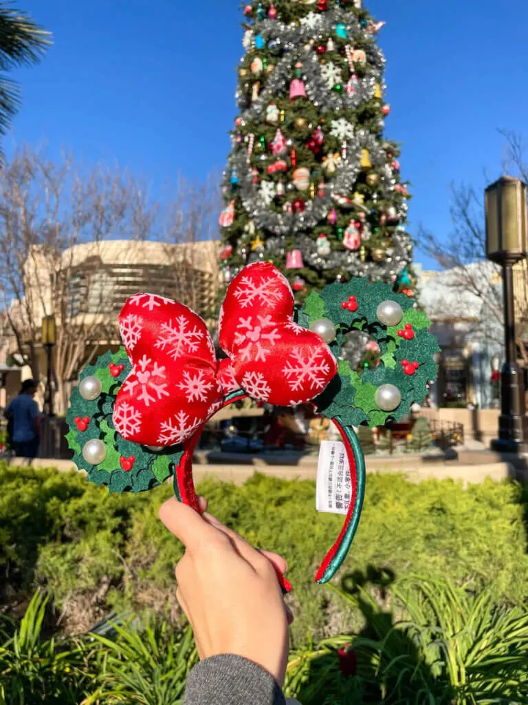 Image of Christmas wreath Minnie Mouse ears in front of a Christmas tree at Disneyland California.