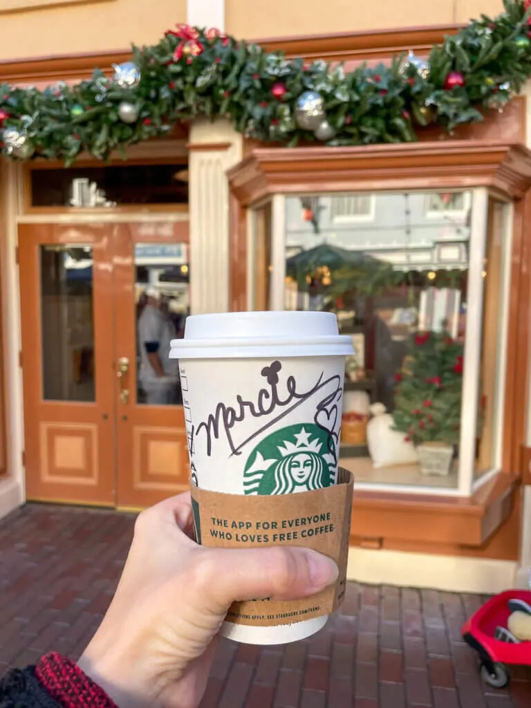 Image of a Starbucks cup with the name Marcie on it with a Mickey Mouse as the dot on the i