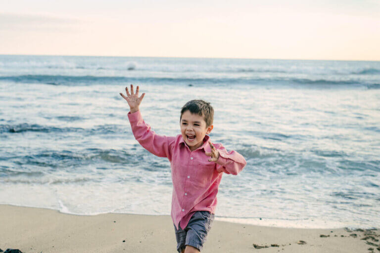 Find out the best things to do on the Big Island with kids by a mom who's done it many times! Image of a boy smiling and running on the beach in Kona Hawaii
