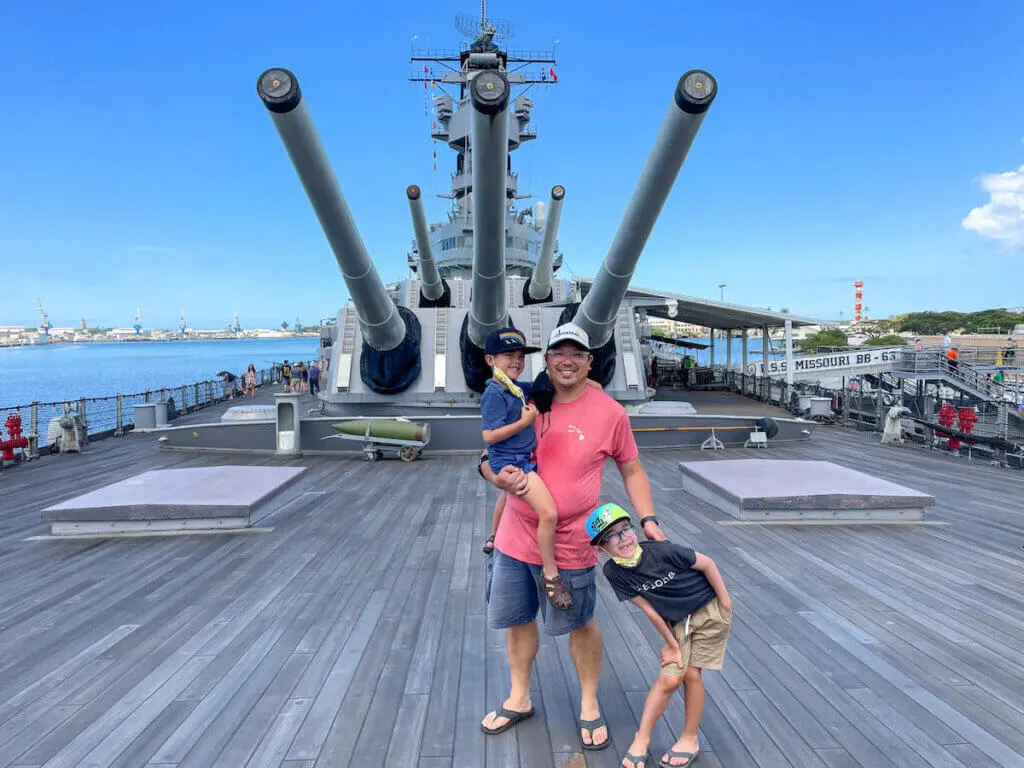 Image of a dad and two boys posing on the deck of the USS Battleship Missouri, a top Pearl Harbor attraction.