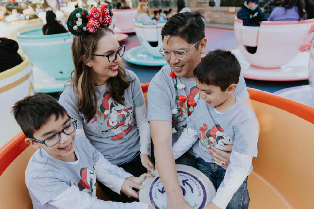 Image of a family wearing matching Mickey shirts sitting in the teacup ride at Disneyland.