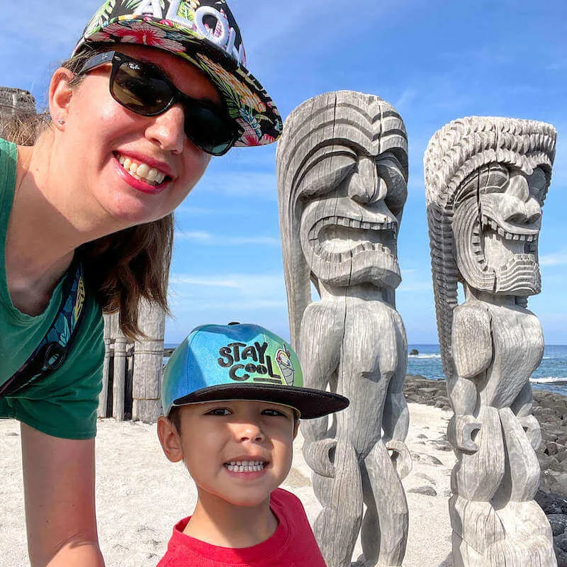 Image of a mom and boy taking a selfie with tiki statues in Hawaii.
