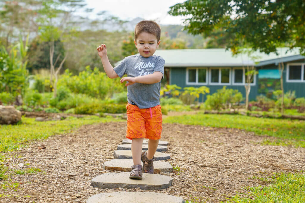 Image of a toddler running on stepping stones on Kauai.