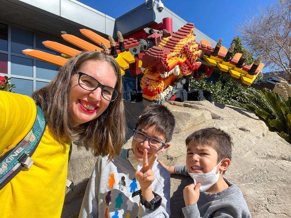 Image of a mom and two boys taking a selfie in front of a LEGO dragon at LEGOLAND California.
