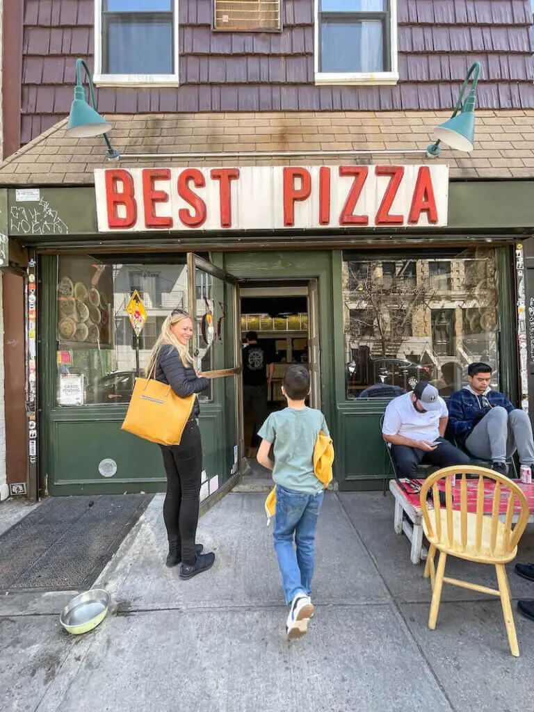 Image of a lady and boy entering a restaurant called Best Pizza