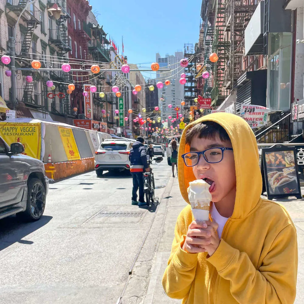 Image of boy wearing a yellow hoodie eating ice cream cone in Chinatown
